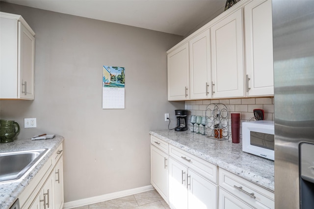 3913 Lawnwoods Dr, Des Moines, IA 50310 - kitchen with freestanding refrigerator, white microwave, decorative backsplash, and white cabinetry