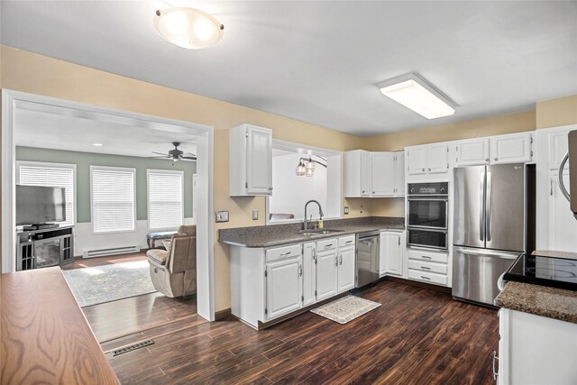 1034 66th St, Windsor Heights, IA 50324 - kitchen with stainless steel appliances, a baseboard heating unit, a warming drawer, dark countertops, and a ceiling fan