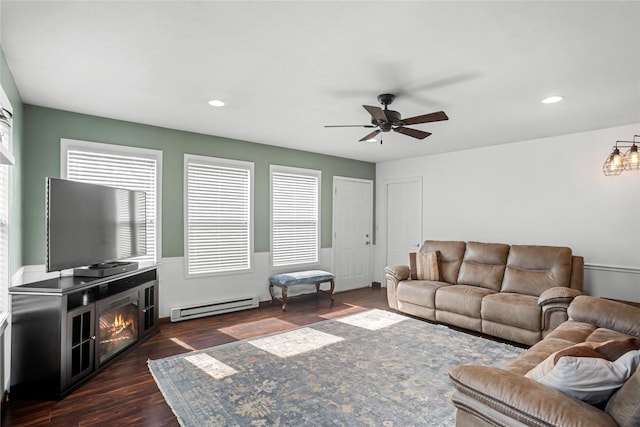 1034 66th St, Windsor Heights, IA 50324 - living room with a baseboard heating unit, ceiling fan, dark wood-style floors, recessed lighting, and a lit fireplace