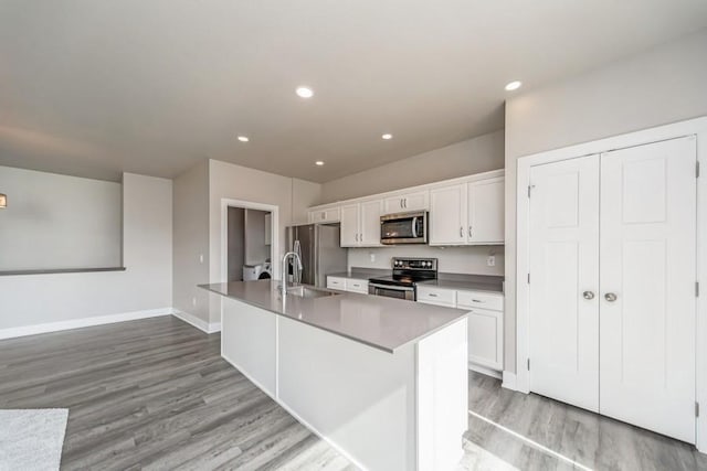 1636 S Redtail Ave, West Des Moines, IA 50265 - kitchen featuring stainless steel appliances, light wood-style flooring, white cabinets, a center island with sink, and recessed lighting