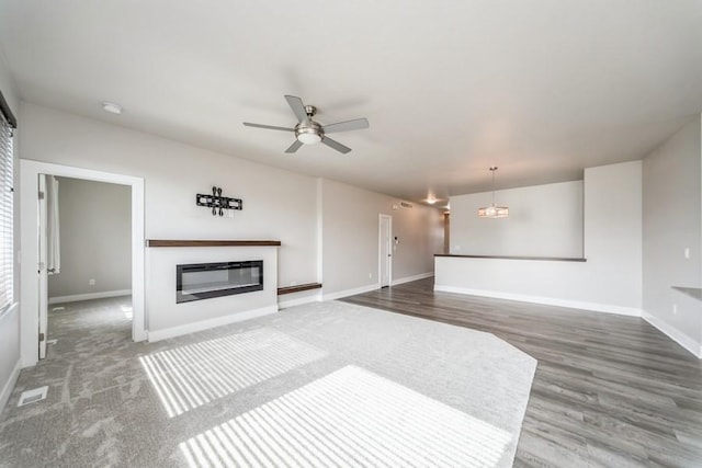 1636 S Redtail Ave, West Des Moines, IA 50265 - unfurnished living room with a glass covered fireplace, ceiling fan, and wood finished floors