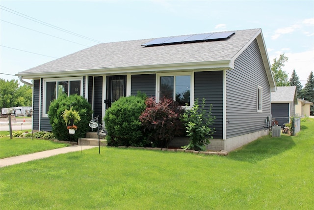 111 S 3rd Ave, Huxley, IA 50124 - view of front of house with roof mounted solar panels, a shingled roof, and a front lawn