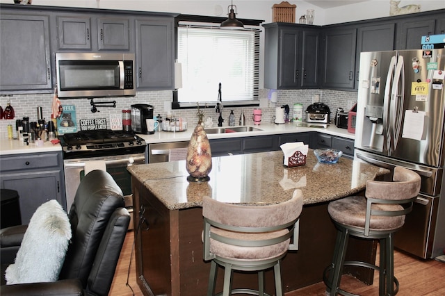 111 S 3rd Ave, Huxley, IA 50124 - kitchen with stainless steel appliances, a center island, backsplash, a kitchen bar, and light wood-style floors