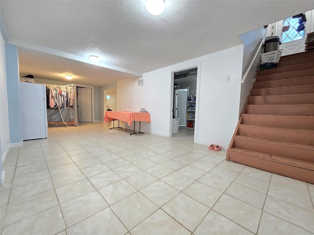 335 Palomino Pkwy, Des Moines, IA 50320 - finished below grade area featuring freestanding refrigerator, a textured ceiling, stairs, and light tile patterned floors