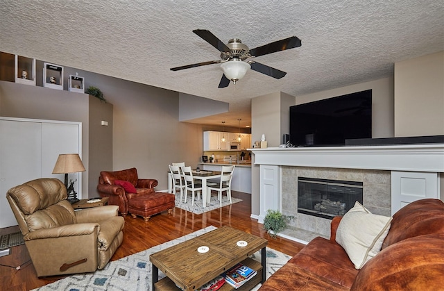 57 SE Meadowlark Ct, Waukee, IA 50263 - living room with wood finished floors, ceiling fan, a textured ceiling, and a tile fireplace