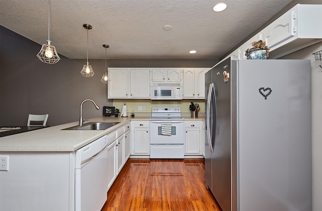 57 SE Meadowlark Ct, Waukee, IA 50263 - kitchen with white appliances, a peninsula, dark wood finished floors, white cabinetry, and a textured ceiling