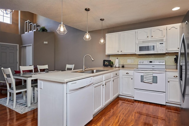 57 SE Meadowlark Ct, Waukee, IA 50263 - kitchen featuring white appliances, a peninsula, dark wood-type flooring, and white cabinetry