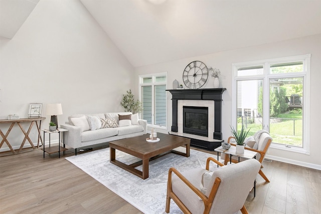 8151 Chambery Blvd, Johnston, IA 50131 - living room featuring high vaulted ceiling, light wood-type flooring, healthy amount of natural light, and a glass covered fireplace