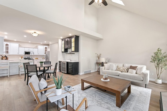 8151 Chambery Blvd, Johnston, IA 50131 - living area with wine cooler, a ceiling fan, light wood-style floors, high vaulted ceiling, and recessed lighting