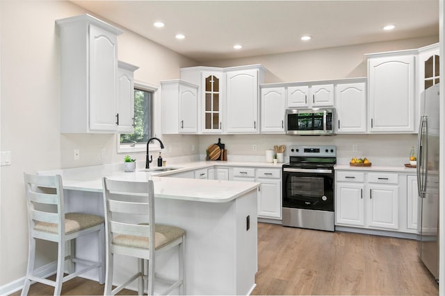 8151 Chambery Blvd, Johnston, IA 50131 - kitchen featuring appliances with stainless steel finishes, a peninsula, glass insert cabinets, white cabinets, and recessed lighting