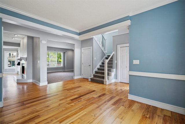 4108 158th Cir, Urbandale, IA 50323 - spare room with stairway, a warm lit fireplace, wood-type flooring, and ornamental molding