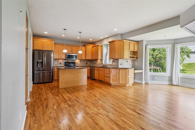 4108 158th Cir, Urbandale, IA 50323 - kitchen featuring appliances with stainless steel finishes, light wood-type flooring, backsplash, a center island, and dark countertops