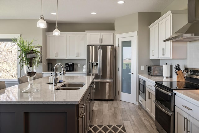 3210 NE 17th St, Ankeny, IA 50021 - kitchen with stainless steel appliances, wall chimney exhaust hood, a center island with sink, backsplash, and light wood-style floors