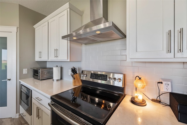 3210 NE 17th St, Ankeny, IA 50021 - kitchen featuring wall chimney exhaust hood, appliances with stainless steel finishes, white cabinetry, tasteful backsplash, and light stone countertops