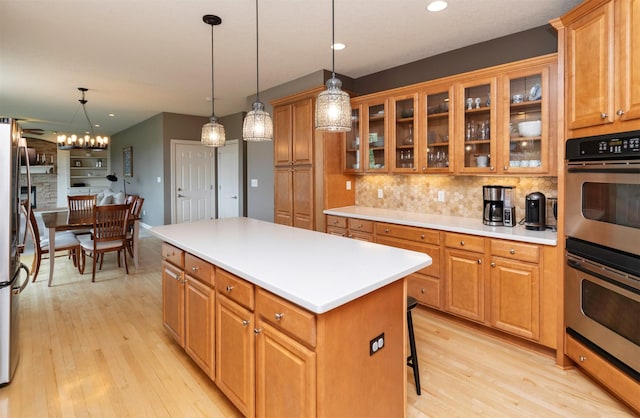 12602 Winston Ave, Urbandale, IA 50323 - kitchen with stainless steel appliances, light wood-type flooring, a center island, decorative backsplash, and pendant lighting