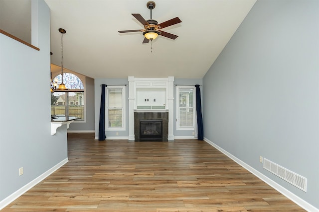 1736 Ashwood Dr SW, Altoona, IA 50009 - unfurnished living room with vaulted ceiling, a ceiling fan, a tiled fireplace, light wood-style flooring, and a chandelier