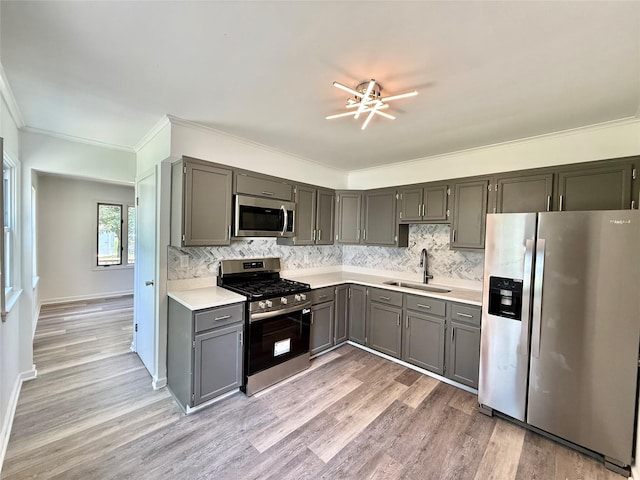 2000 E 21st St, Des Moines, IA 50317 - kitchen featuring stainless steel appliances, light countertops, backsplash, light wood-style floors, and crown molding