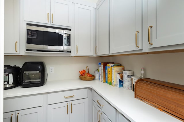1302 S L Ct, Indianola, IA 50125 - kitchen with stainless steel microwave, light countertops, and white cabinets