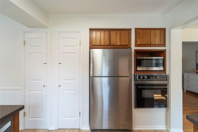 912 23rd St, West Des Moines, IA 50265 - kitchen with stainless steel appliances, brown cabinets, dark countertops, and light wood-type flooring