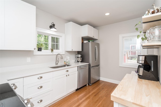 5617 Grand Ave, Des Moines, IA 50312 - kitchen featuring appliances with stainless steel finishes, white cabinetry, light wood-type flooring, and recessed lighting