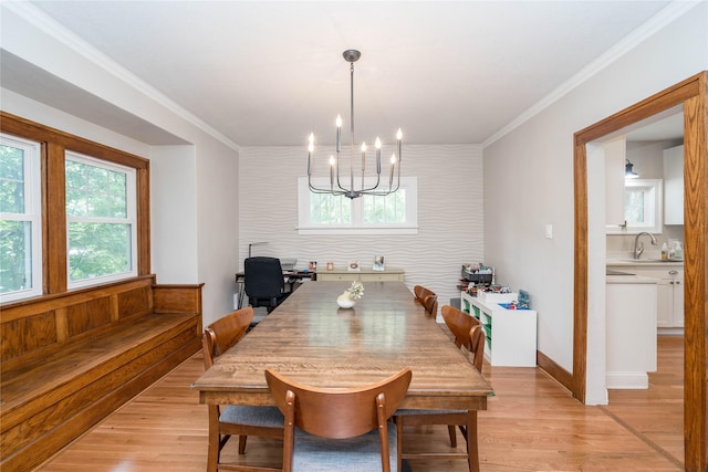 5617 Grand Ave, Des Moines, IA 50312 - dining space with light wood-style flooring, a chandelier, crown molding, and an accent wall