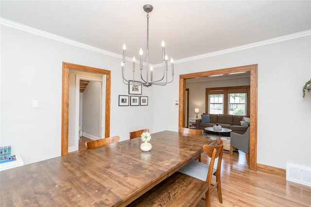 5617 Grand Ave, Des Moines, IA 50312 - dining area with crown molding, light wood-type flooring, and a chandelier