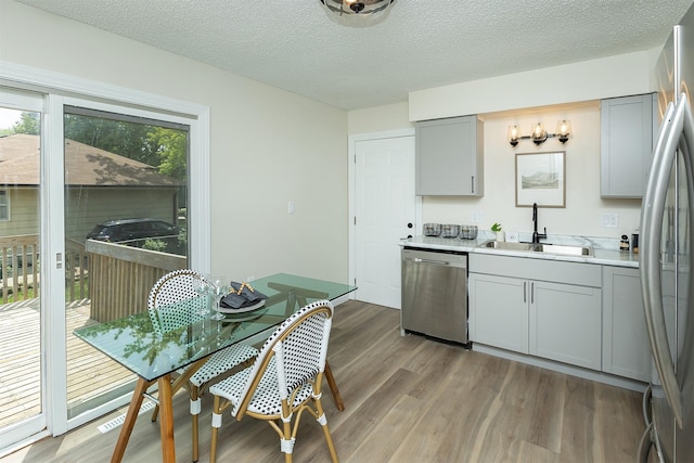 401 NE Harvey St, Grimes, IA 50111 - kitchen featuring appliances with stainless steel finishes, gray cabinets, light wood finished floors, and a textured ceiling