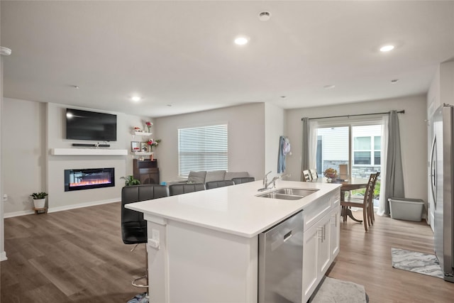 4410 NE Mongoose Ln, Ankeny, IA 50021 - kitchen with stainless steel appliances, white cabinetry, an island with sink, light wood finished floors, and open floor plan