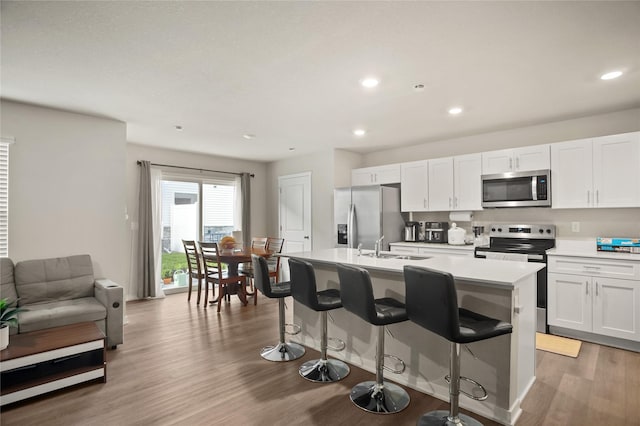 4410 NE Mongoose Ln, Ankeny, IA 50021 - kitchen with appliances with stainless steel finishes, an island with sink, a breakfast bar, light wood-style floors, and light countertops