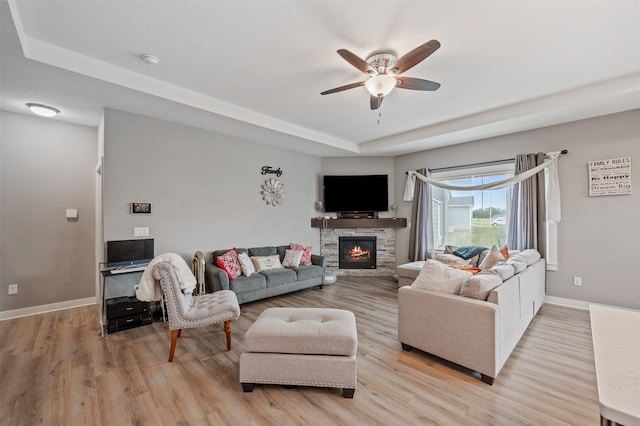 5397 Brook View Ave, Des Moines, IA 50317 - living area with a tray ceiling, ceiling fan, light wood-type flooring, and a fireplace