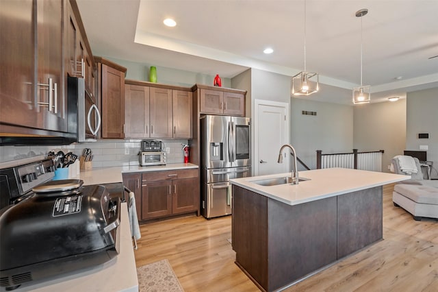 5397 Brook View Ave, Des Moines, IA 50317 - kitchen with appliances with stainless steel finishes, light wood-style floors, decorative backsplash, light countertops, and hanging light fixtures