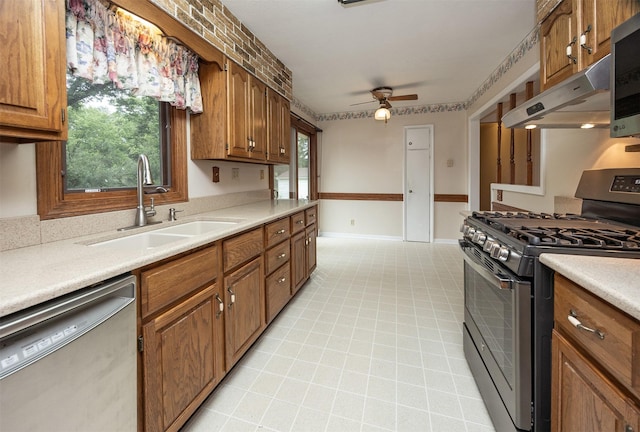 2217 Meadow Ln, West Des Moines, IA 50265 - kitchen featuring appliances with stainless steel finishes, under cabinet range hood, a ceiling fan, brown cabinetry, and light countertops