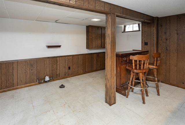 2217 Meadow Ln, West Des Moines, IA 50265 - below grade area featuring a bar, wooden walls, light flooring, wainscoting, and a paneled ceiling