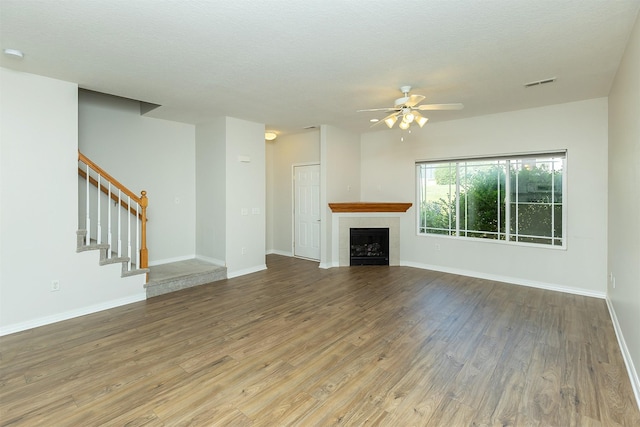 2240 Hart Ave Unit 4, Des Moines, IA 50320 - unfurnished living room featuring ceiling fan, wood finished floors, stairs, and a tile fireplace