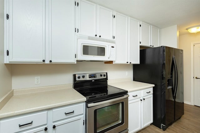 2240 Hart Ave Unit 4, Des Moines, IA 50320 - kitchen with stainless steel electric range, white microwave, black fridge, white cabinetry, and light countertops