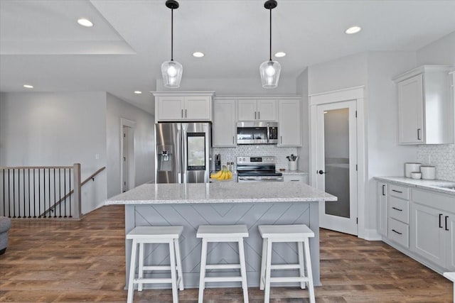 519 Alpha St NW, Bondurant, IA 50035 - kitchen with appliances with stainless steel finishes, decorative backsplash, white cabinets, recessed lighting, and a kitchen bar