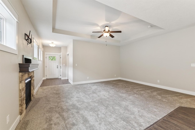 14335 Holcomb Ave, Urbandale, IA 50323 - unfurnished living room featuring a tray ceiling, carpet, a ceiling fan, and a fireplace