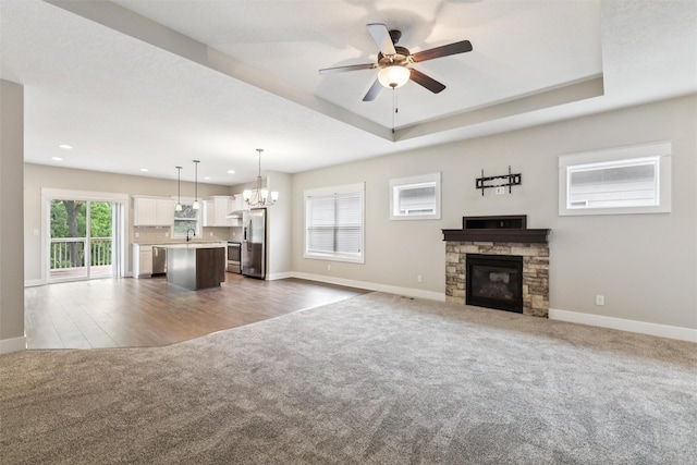 14335 Holcomb Ave, Urbandale, IA 50323 - unfurnished living room with carpet flooring, ceiling fan, a chandelier, a stone fireplace, and recessed lighting