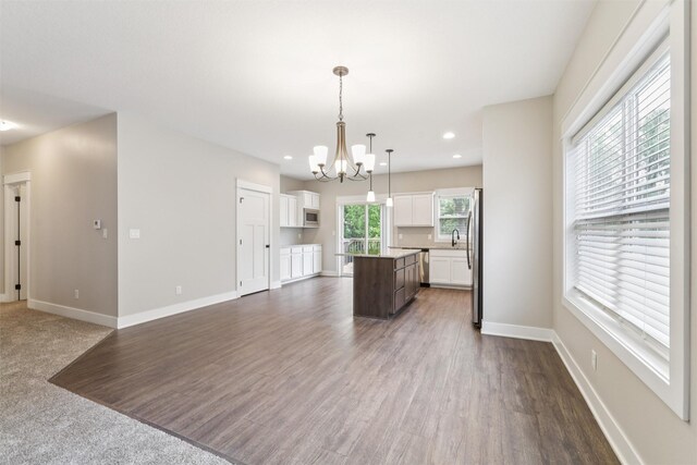 14335 Holcomb Ave, Urbandale, IA 50323 - kitchen with a kitchen island, a chandelier, white cabinets, open floor plan, and recessed lighting