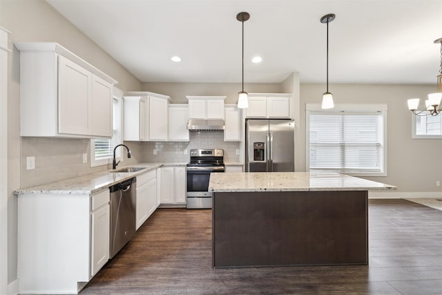 14335 Holcomb Ave, Urbandale, IA 50323 - kitchen with appliances with stainless steel finishes, under cabinet range hood, a kitchen island, healthy amount of natural light, and recessed lighting