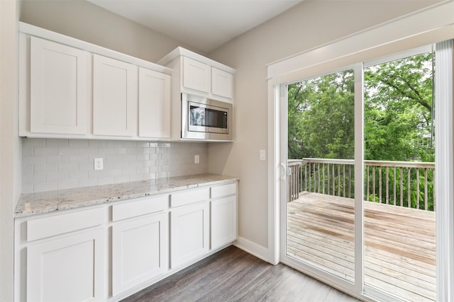 14335 Holcomb Ave, Urbandale, IA 50323 - kitchen with stainless steel microwave, decorative backsplash, wood finished floors, white cabinets, and light stone countertops