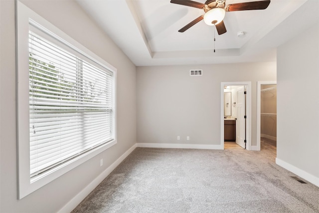 14335 Holcomb Ave, Urbandale, IA 50323 - unfurnished bedroom featuring light carpet, a raised ceiling, a spacious closet, ceiling fan, and a closet