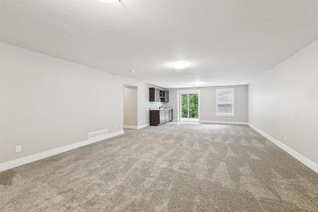 14335 Holcomb Ave, Urbandale, IA 50323 - unfurnished living room featuring light colored carpet and a textured ceiling