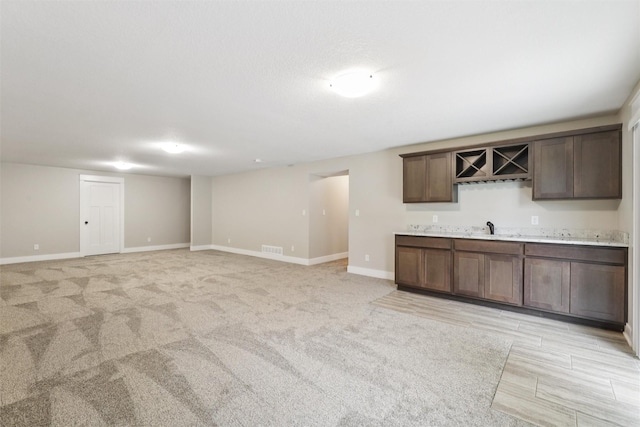14335 Holcomb Ave, Urbandale, IA 50323 - kitchen featuring light countertops, dark brown cabinetry, and light colored carpet