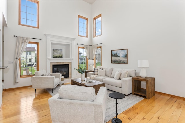 1201 NW Norton St, Grimes, IA 50111 - living room featuring light wood-style floors, a high ceiling, and a tiled fireplace