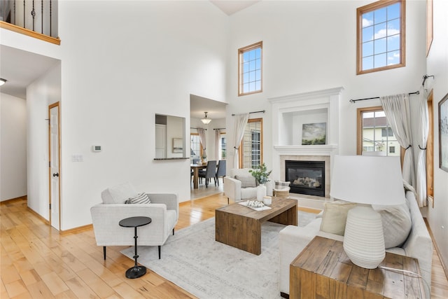 1201 NW Norton St, Grimes, IA 50111 - living room featuring a high ceiling, healthy amount of natural light, light wood-style flooring, and a fireplace