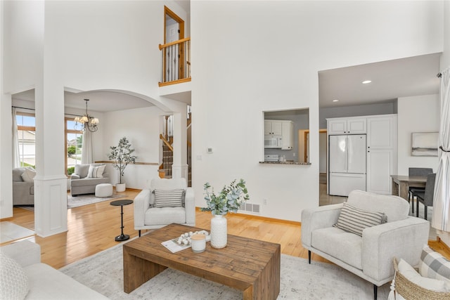 1201 NW Norton St, Grimes, IA 50111 - living room with light wood-type flooring, a chandelier, a high ceiling, arched walkways, and recessed lighting
