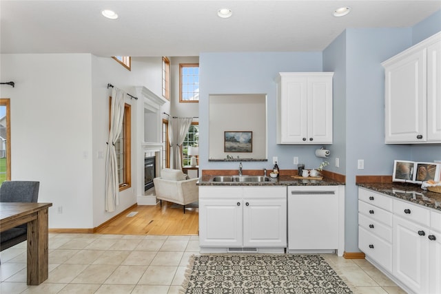 1201 NW Norton St, Grimes, IA 50111 - kitchen featuring white dishwasher, a glass covered fireplace, white cabinets, light tile patterned floors, and recessed lighting