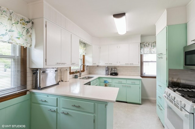 3709 Aurora Ave, Des Moines, IA 50310 - kitchen featuring decorative backsplash, gas range gas stove, light countertops, stainless steel microwave, and white cabinetry
