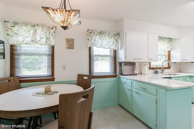 3709 Aurora Ave, Des Moines, IA 50310 - kitchen with decorative backsplash, light countertops, a peninsula, white cabinets, and pendant lighting